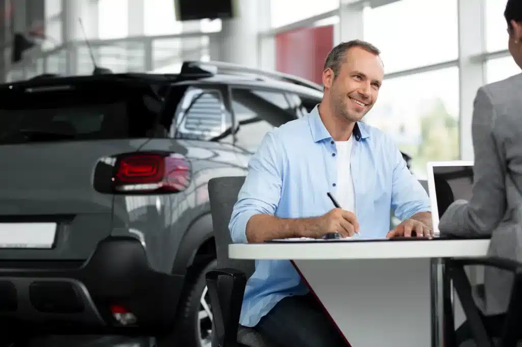 Man signing papers at car dealership
