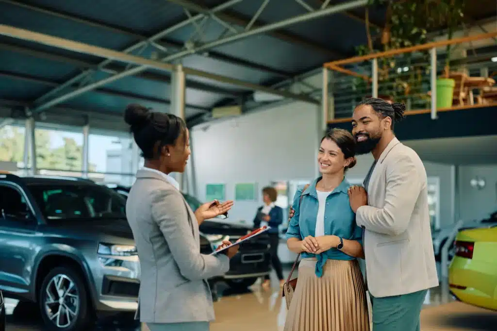 Salesperson assisting couple at car dealership