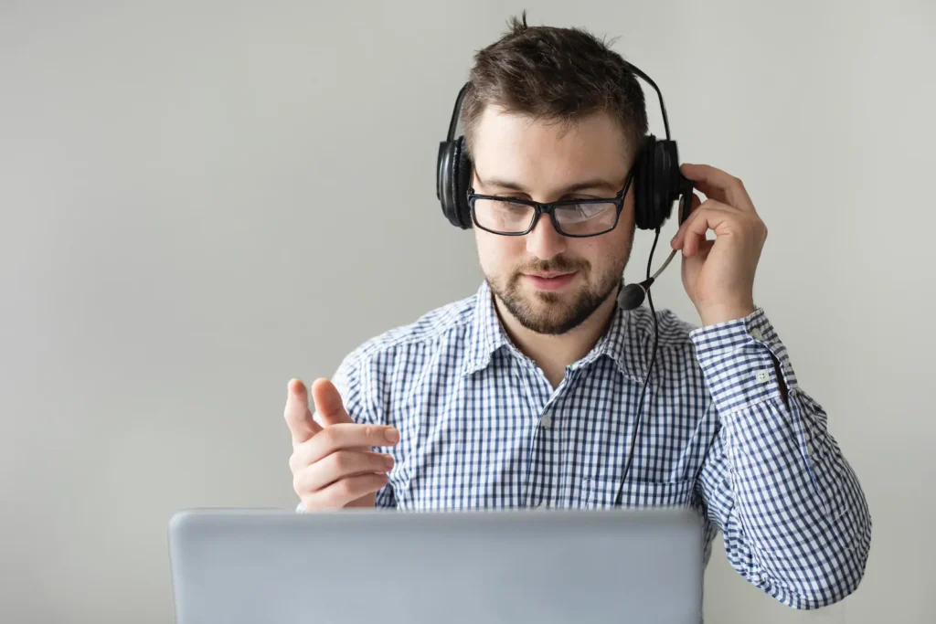 Man with headset video conferencing on laptop