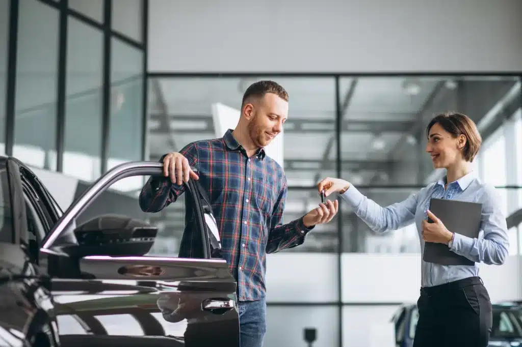 Salesperson handing car keys to customer.